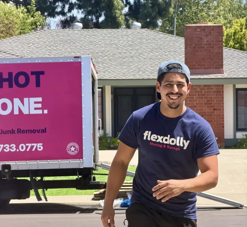 Flexdolly mover in a navy Moving and Storage tee walking back to the pink truck