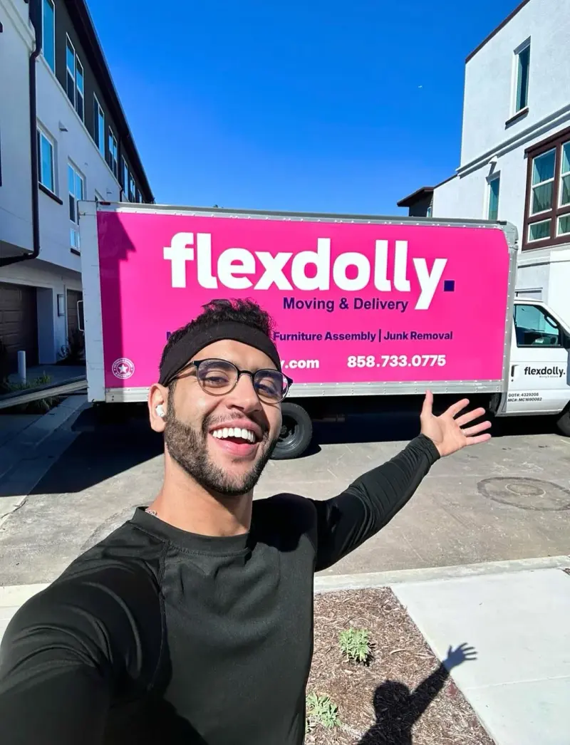 Nas, founder of Flexdolly, smiling and presenting a hot-pink Flexdolly truck under a blue San Diego sky