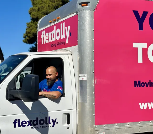 Flexdolly driver in the cab of a pink Flexdolly box truck