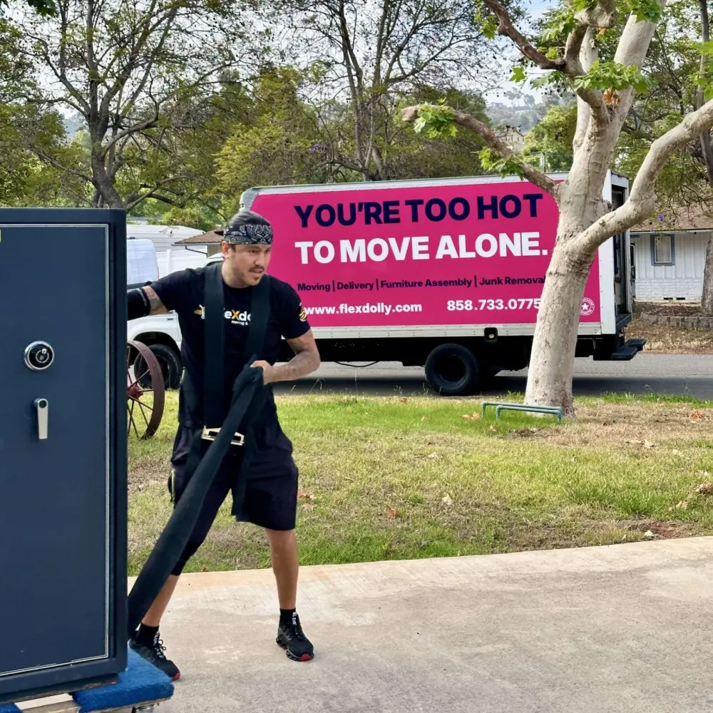 Flexdolly mover strapping a safe with the pink slogan truck behind