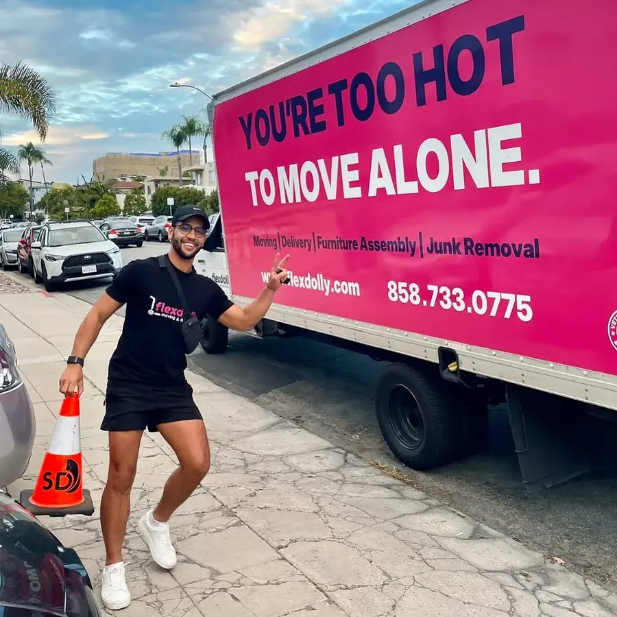 Flexdolly mover pointing at the slogan on a pink Flexdolly truck